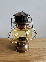 front view showing brass cage, amber glass globe, copper base and chimney