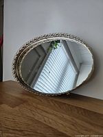 Angled view of oval mirror showing filigree frame and mirror surface