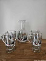 Group shot showing four footed mugs and matching carafe with winter sleigh design