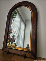 Full view of arched wood-framed mirror standing upright
