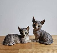 Both ceramic tabby cat figurines, seated and lying