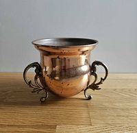 Front view of copper planter showing brass handles and feet