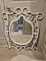 Front view of white rattan mirror leaning on door