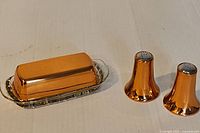 Butter dish with copper lid on glass tray and two matching shakers
