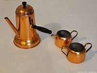 Coffee pot, creamer, sugar bowl grouped on white surface