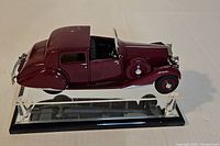 Side view of burgundy 1938 Rolls-Royce die-cast model on acrylic display stand