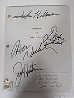 Full view of the signed screenplay showing brass fasteners and four signatures