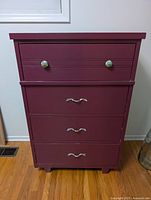 Front view of plum dresser showing four drawers and mixed hardware
