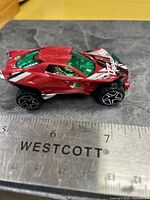 Left side view of red Metal Machines car beside ruler showing length