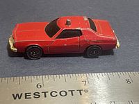 Left side view of red Ford Gran Torino model with ruler for scale