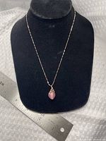 Full view of necklace on display bust with ruler for scale