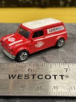 Left front quarter view of the red/white ’67 Austin Mini Van with Campbell’s graphics placed beside ruler