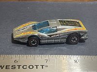 Left side view of car showing body color, decals, redline wheels, and size reference with ruler