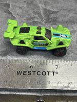 Left side view of green Quicksand car next to ruler showing about 3 inches length