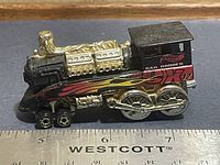 Left side view of Hot Wheels Rail Rodder showing flame graphics, wheels and ruler for scale