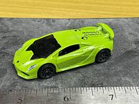 Left side view of lime-green Lamborghini Sesto Elemento toy car next to ruler