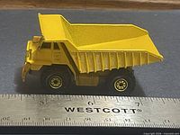 Left side profile of yellow Hot Wheels dump truck with ruler