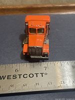 Front view of orange Hot Wheels Road Hog semi cab with ruler for scale