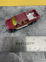 Left front and top view of maroon Ford F-150 Hot Wheels truck next to ruler for size reference