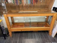 Full view of wooden frame display cabinet with glass top and shelf