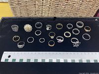 All twenty rings laid out on black velvet with ruler for scale