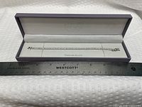 Bracelet laid in open Lulea case beside ruler showing length