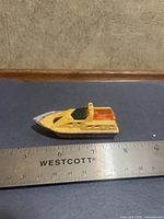 Left side view of yellow Matchbox rescue boat beside ruler showing length