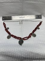 Full view of necklace with ruler for scale, showing bead pattern and charms