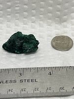 Malachite specimen beside ruler and coin, top view