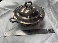 Top view of silver-plated covered dish showing handles, finial, and overall form