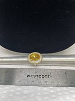 Top view showing oval yellow stone with clear halo and measurement scale