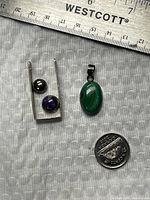 Overall view of both pendants with coin and ruler for scale
