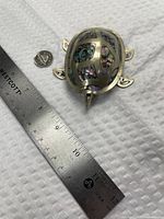 Top view of silver turtle container with ruler and coin for scale