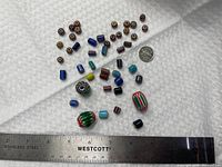 Overall lot with ruler and dime for scale showing assortment of beads