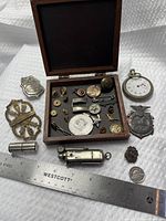 Open case with assorted contents, pocket watch, badges, lighter, ruler for scale