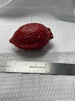 Closed red walnut-form nutcracker beside ruler showing ~4 in. length