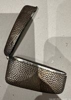 Case standing open showing hammered texture, hinge and interior rim hallmarks