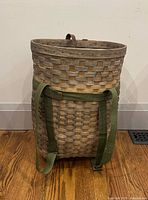Front view of woven pack basket showing green canvas shoulder straps