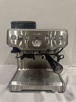 Front view of Breville stainless steel espresso machine showing gauge, controls, steam wand and portafilter