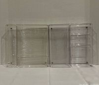 Two clear acrylic drawer organizers side by side showing compartment layouts