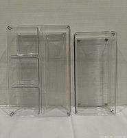 Two clear plastic drawer organizers standing upright showing compartment layout and textured bases