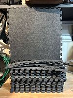 Stack of 28 interlocking dark grey foam floor tiles