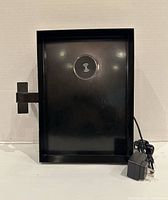 Front view of black metal charging tray showing Qi pad and attached power adapter