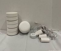 Stack of mesh routers, separate rounded router, power adapters and cables