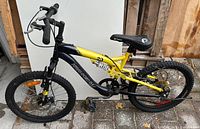 Full side view of yellow and black Kranked Factor 20 youth mountain bike on patio