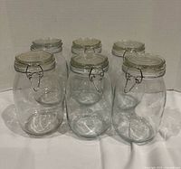 Six clear glass clamp‐top storage jars arranged in two rows