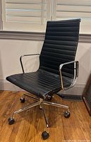 Front view of black ribbed leather high-back swivel office chair with chrome frame and caster base