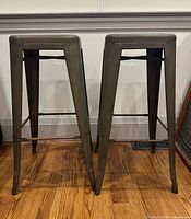Front view of two metal bar stools showing height and leg design