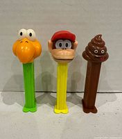 Front view of three PEZ dispensers showing character heads and colored stems