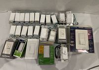 Group of loose and packaged Lutron dimmers and switches laid out on white surface